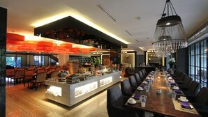 A modern hotel lobby with a long dining table, a bar area, and a chandelier. - Blue Sky Hotel (Balikpapan)