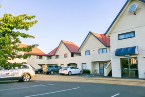 A hotel with a reception area, multiple parking spaces, and a building with a red roof. - Bella Vista Motel Mosgiel (Mosgiel)
