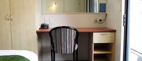 A hotel room with a bed, a desk, a chair, a television, and a door.