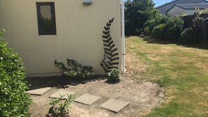 A house with a large fern decoration on the wall, a small window, and a garden with stepping stones. - Bella Vista Motel Mosgiel (Mosgiel)