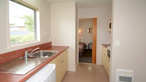 A compact kitchen with a stainless steel sink, a built-in oven, and a microwave. - Bella Vista Motel Mosgiel (Mosgiel)