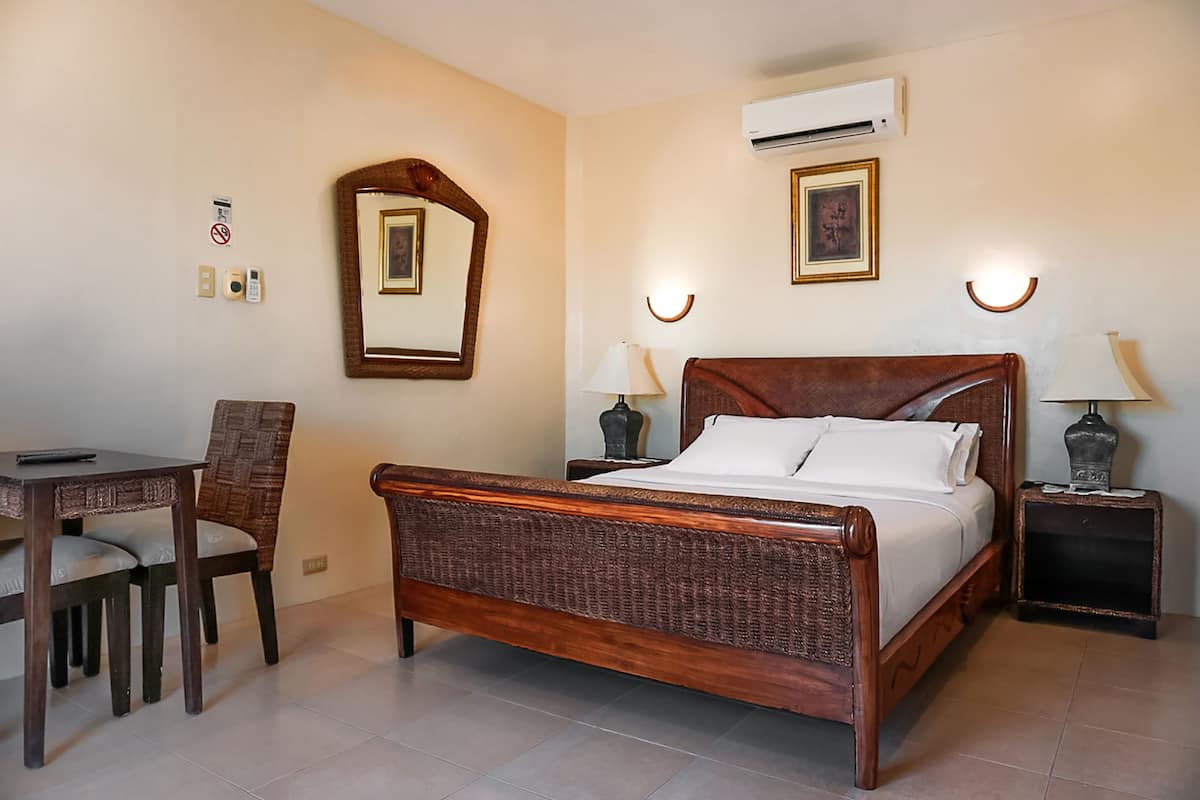 A bedroom with a wooden bed, a desk, and two nightstands with lamps.