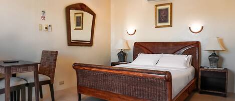 A bedroom with a wooden bed, a desk, and two nightstands with lamps.