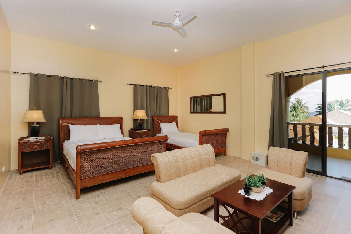 A hotel room with a bed, two bedside tables, a sofa, a coffee table, and a balcony with a view.