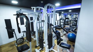 Un gimnasio con equipo de ejercicio variado, incluyendo una caminadora, una elíptica y máquinas de pesas.