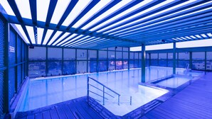 Una piscina interior con plataforma de madera y barandilla de metal.