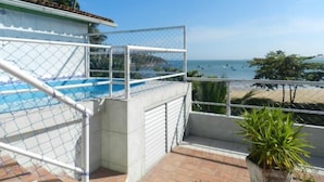 A balcony with a pool, a view of the sea, and a potted plant. - Pousada Caravelas (Guarapari)