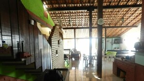 A spacious kitchen with a tiled floor, a brick wall, and a wooden ceiling. - Pousada Caravelas (Guarapari)