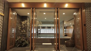 A reception area with a wooden reception desk, a glass partition, and a decorative plant. - OHYA Chain Boutique Motel-Linkou (New Taipei City)