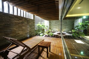 A wooden deck with seating, stone walls, and potted plants. - OHYA Chain Boutique Motel-Linkou (New Taipei City)
