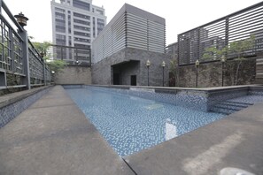 A swimming pool with a tiled floor and a stone wall on one side. - OHYA Chain Boutique Motel-Linkou (New Taipei City)
