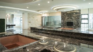 A modern lobby with marble countertops, a stone wall, and a recessed ceiling. - OHYA Chain Boutique Motel-Linkou (New Taipei City)