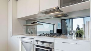 Une cuisine moderne avec des meubles blancs, un four encastré, un lave-vaisselle et une cuisinière à gaz.