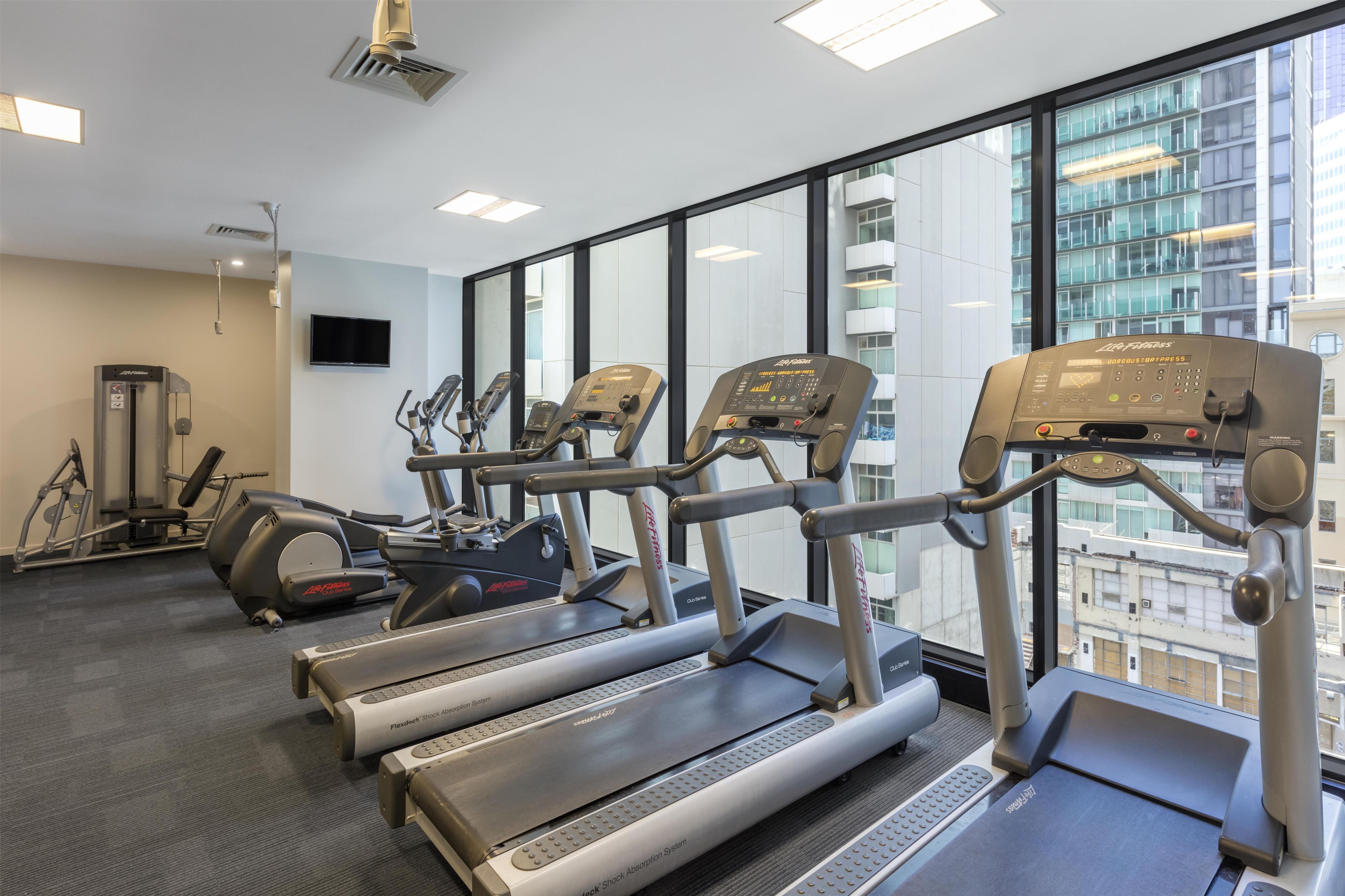 A gym with treadmills, elliptical machines, and a weight machine.