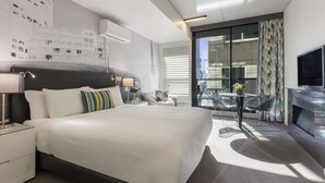 Une chambre d’hôtel moderne dotée d’un grand lit, d’un bureau, d’une chaise, d’une télévision et d’un balcon offrant une vue sur la ville.