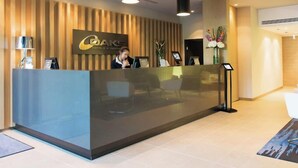 Un espace d’accueil d’hôtel au design moderne, comprenant un comptoir d’accueil, un panneau mural et un présentoir.