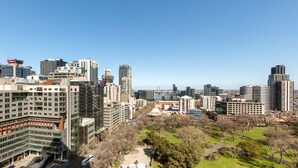 A cityscape with modern high-rise buildings, a park with trees, and a clear sky. - Oaks Melbourne on William Suites (Melbourne)