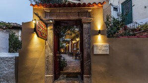 A warmly lit entrance to a building with a sign reading "Pension Dafiti." - Pension Dafni (Nafplio)