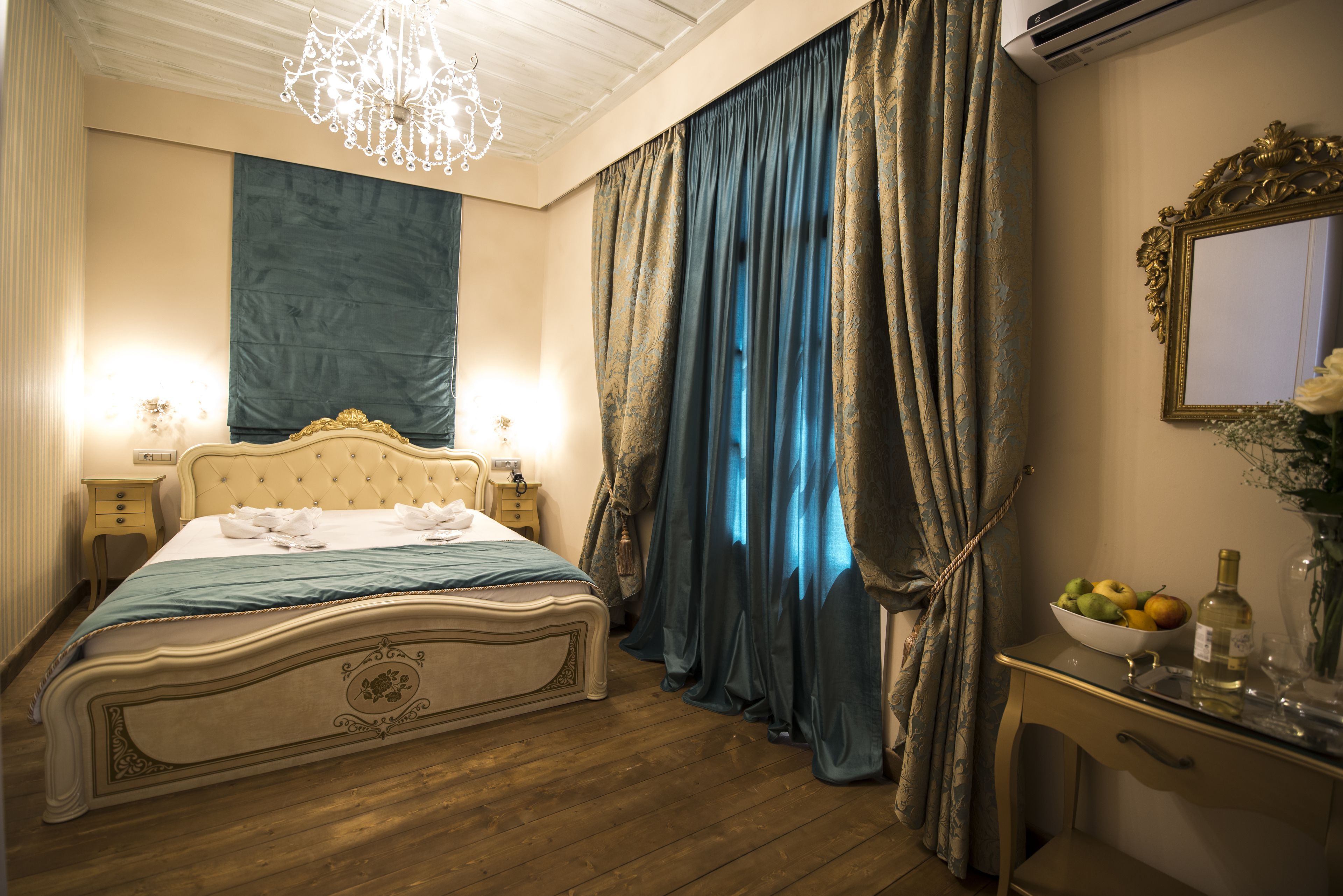 A bedroom with a bed, a nightstand, a dresser, a mirror, and a chandelier.