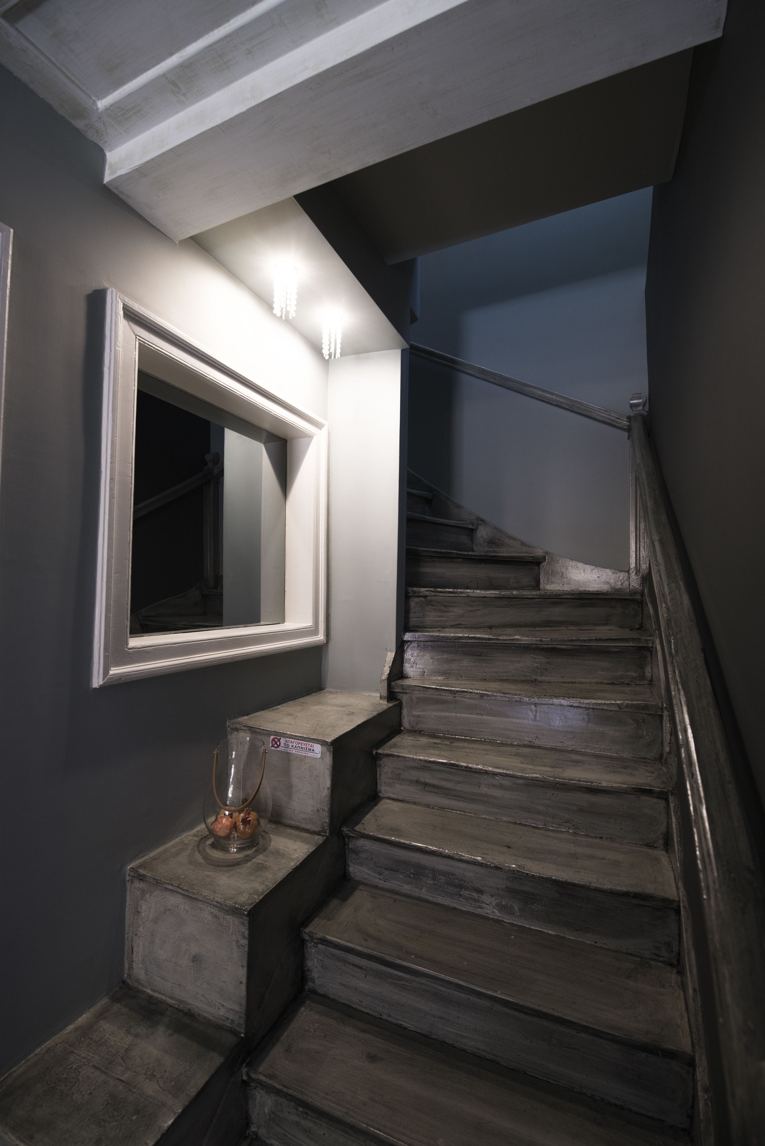 A staircase with a handrail, a wall-mounted mirror, and a small table with a glass vase.