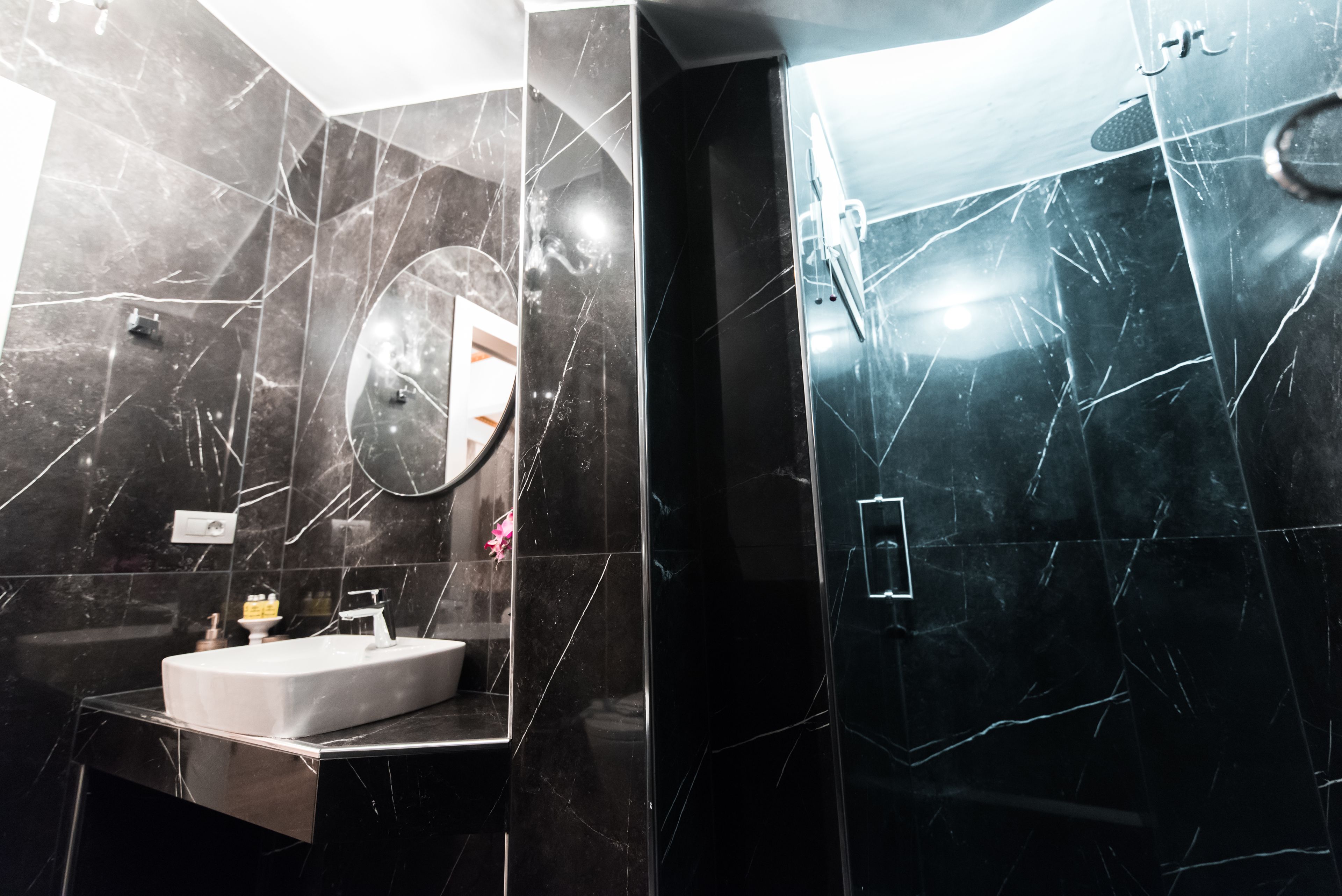 A modern bathroom with a rectangular sink, a mirror, and a shower area.