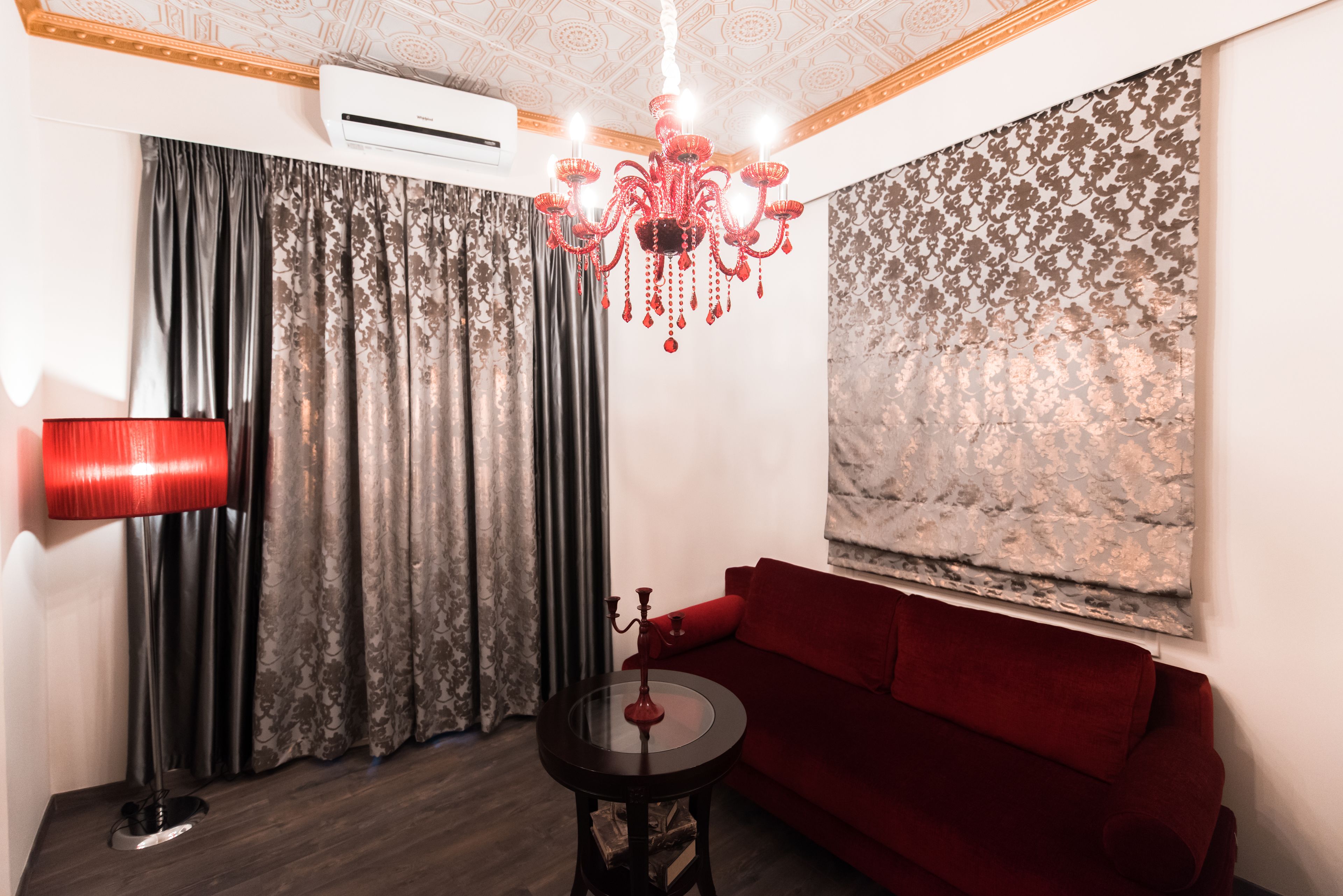 A living room with a red sofa, a chandelier, and a red floor lamp.