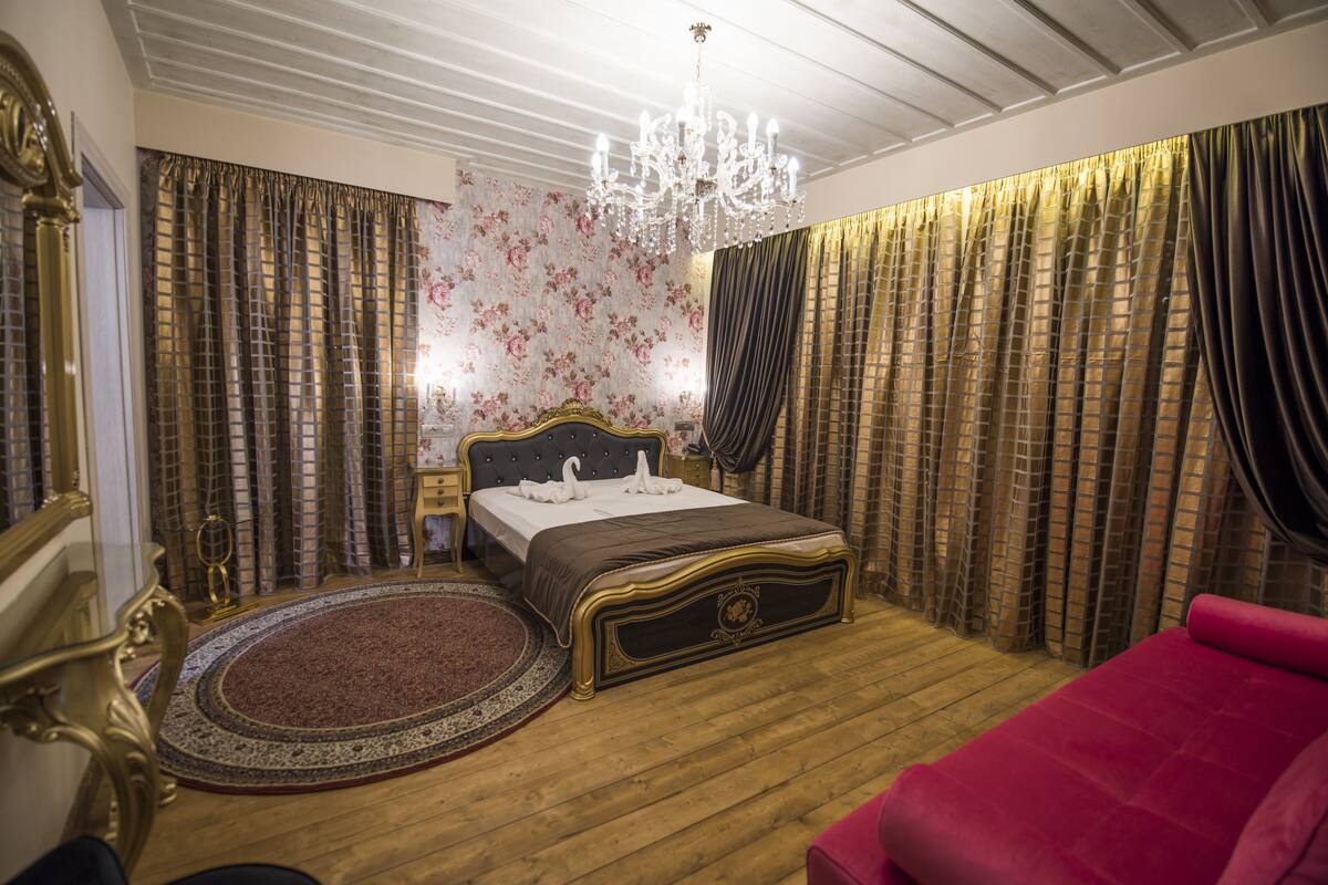 Un dormitorio con una cama grande, una araña y cortinas.