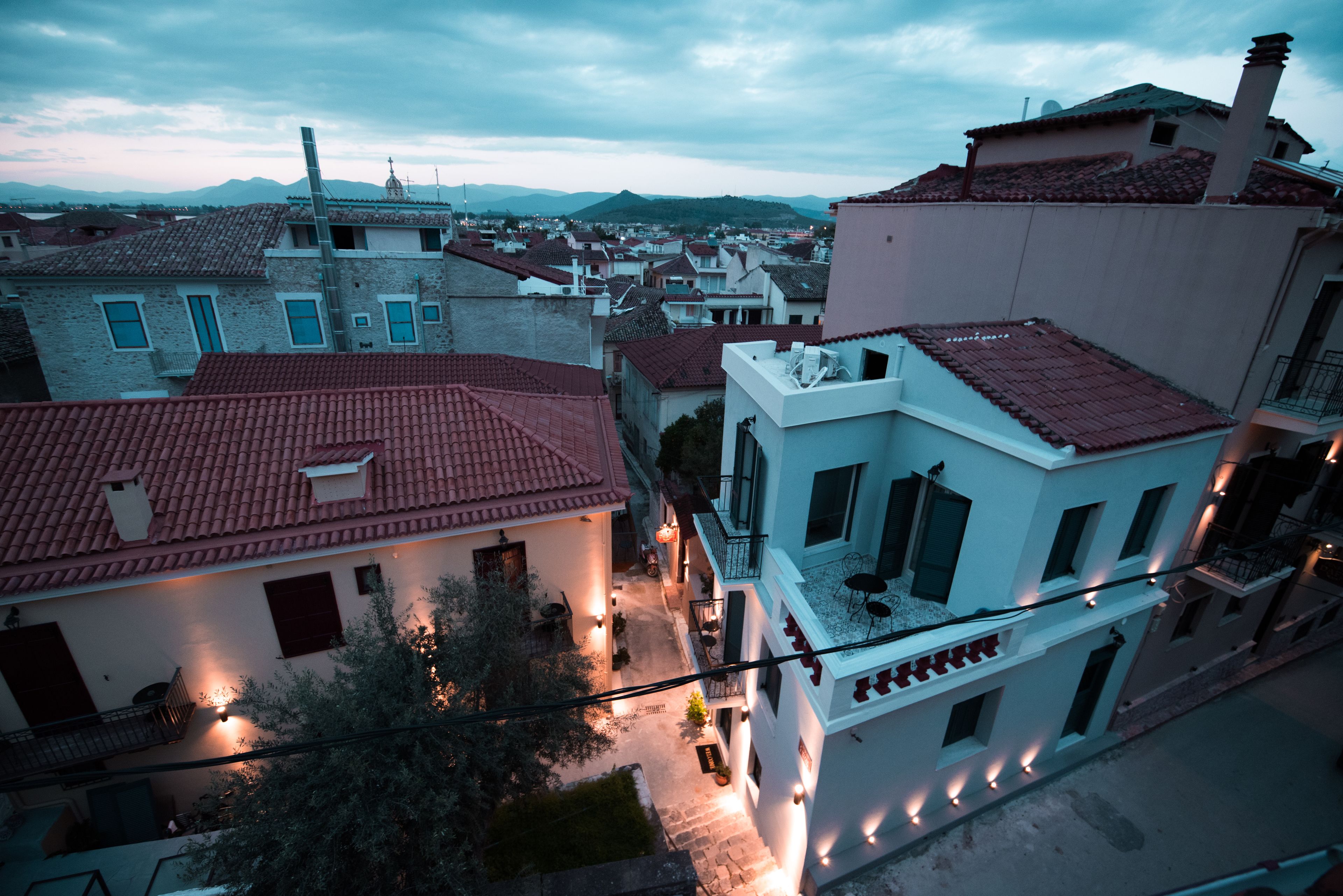 A residential area with buildings featuring red-tiled roofs and white walls, some with balconies and outdoor seating areas.
