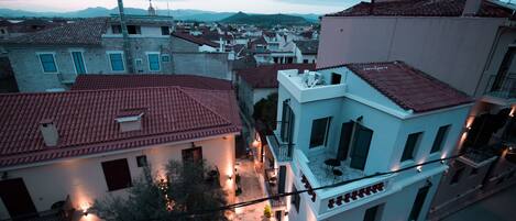 A residential area with buildings featuring red-tiled roofs and white walls, some with balconies and outdoor seating areas.