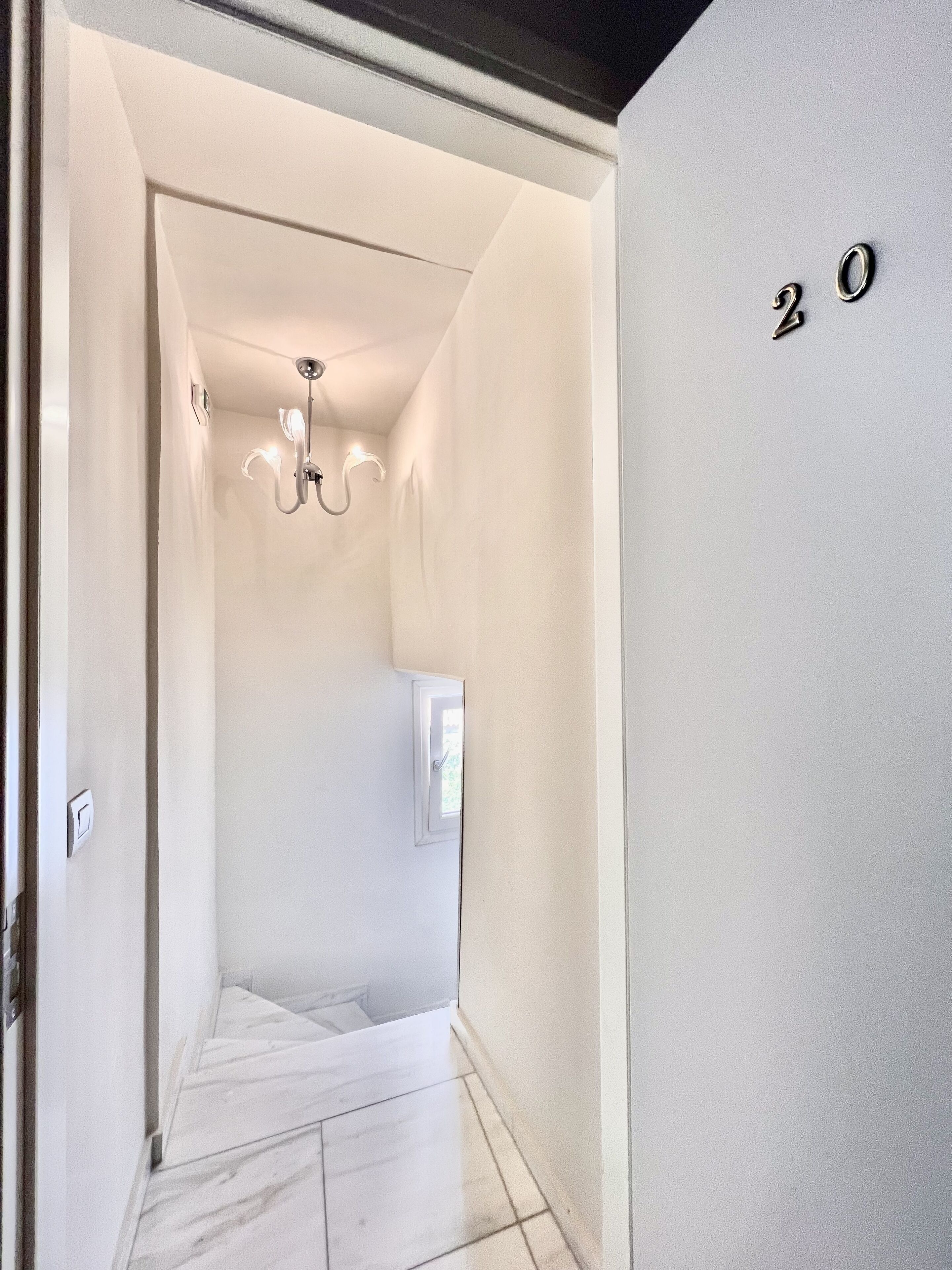 A hallway with a chandelier, a door, and a wall with the number "20".