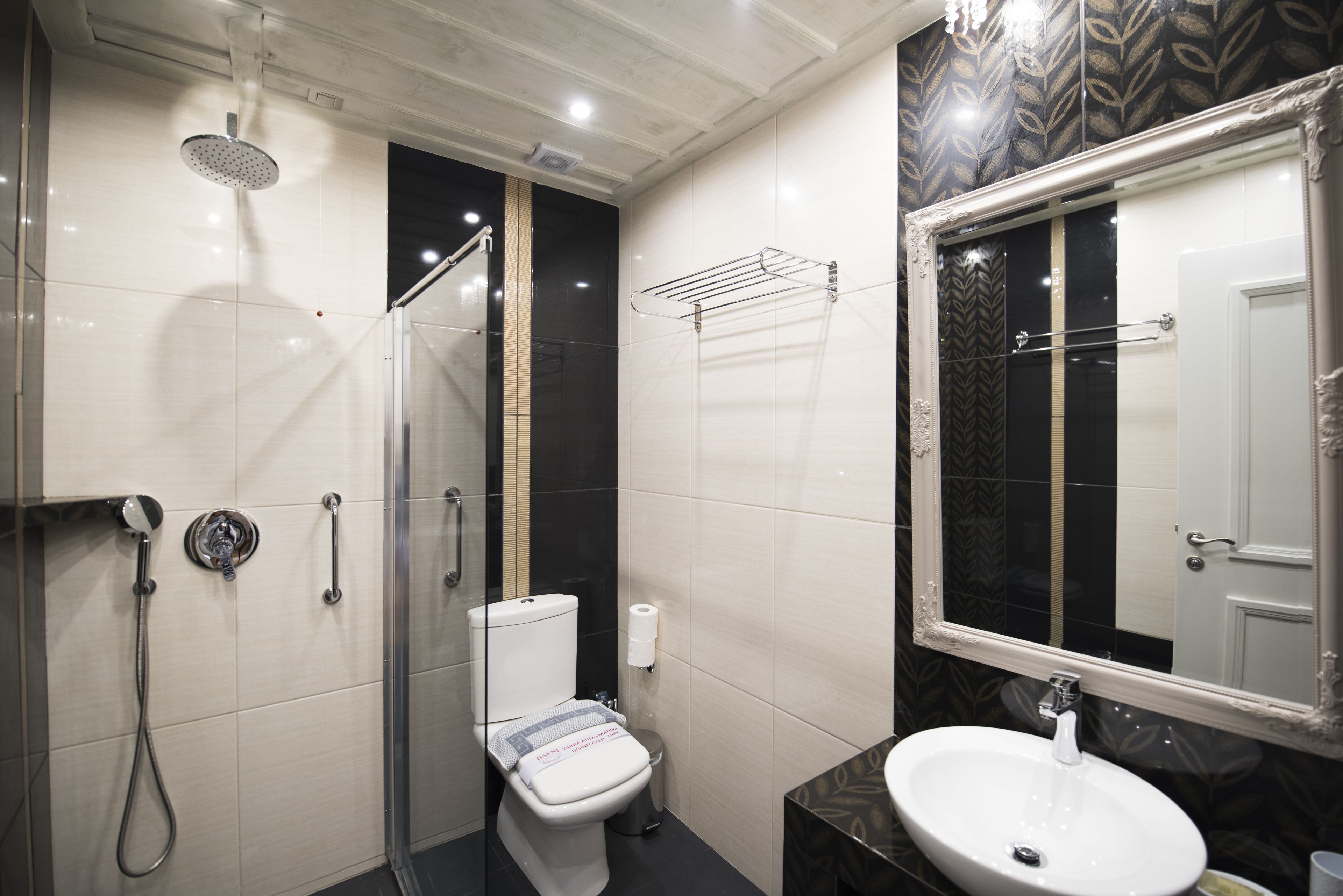 Un baño moderno con ducha de vidrio, inodoro, lavamanos y espejo.