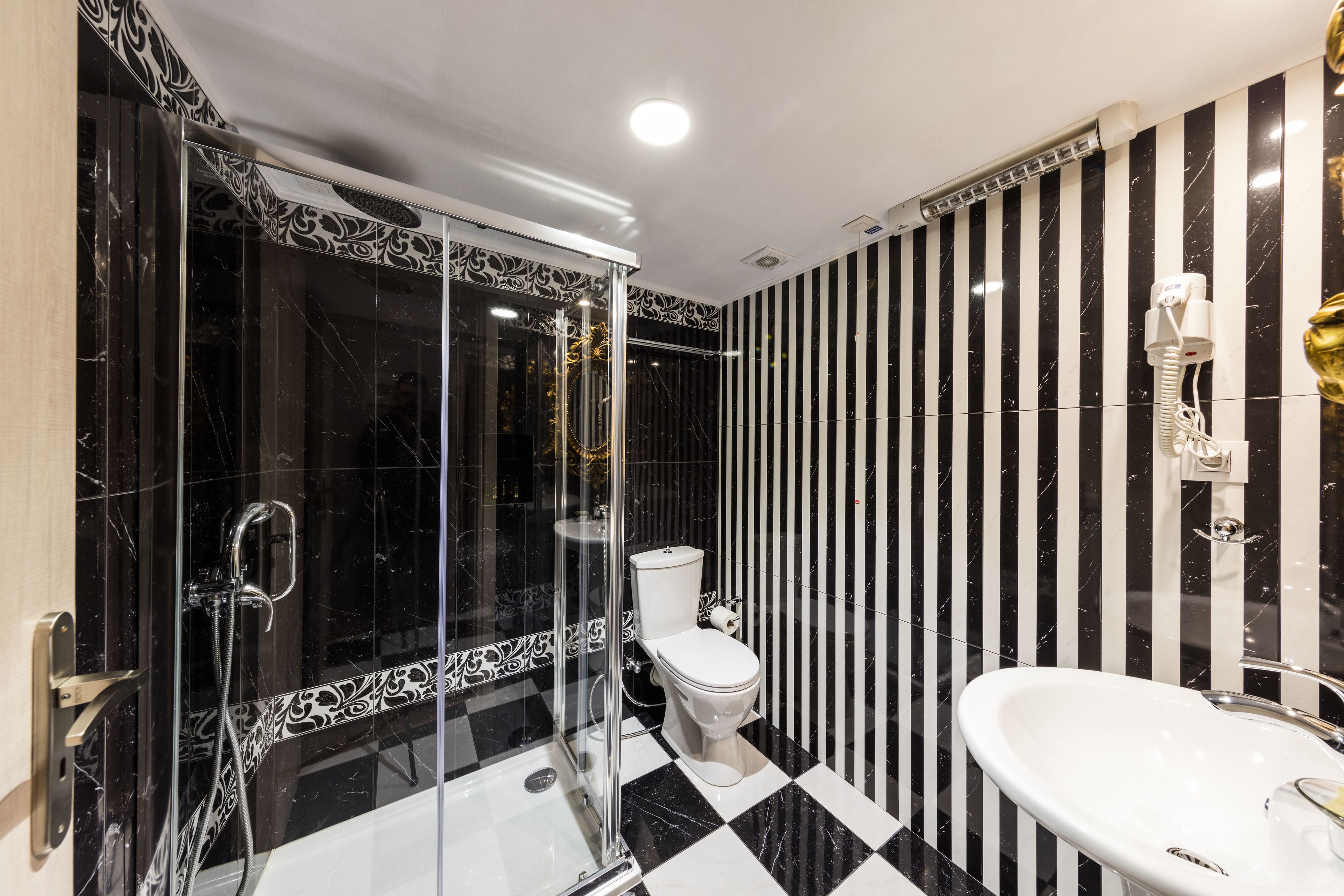 A modern bathroom with a glass-enclosed shower, a white toilet, and a white sink.