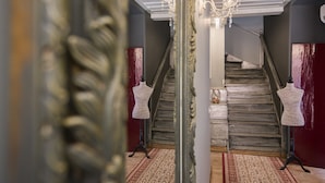 A staircase with a chandelier, a mannequin, and a patterned rug. - Pension Dafni (Nafplio)