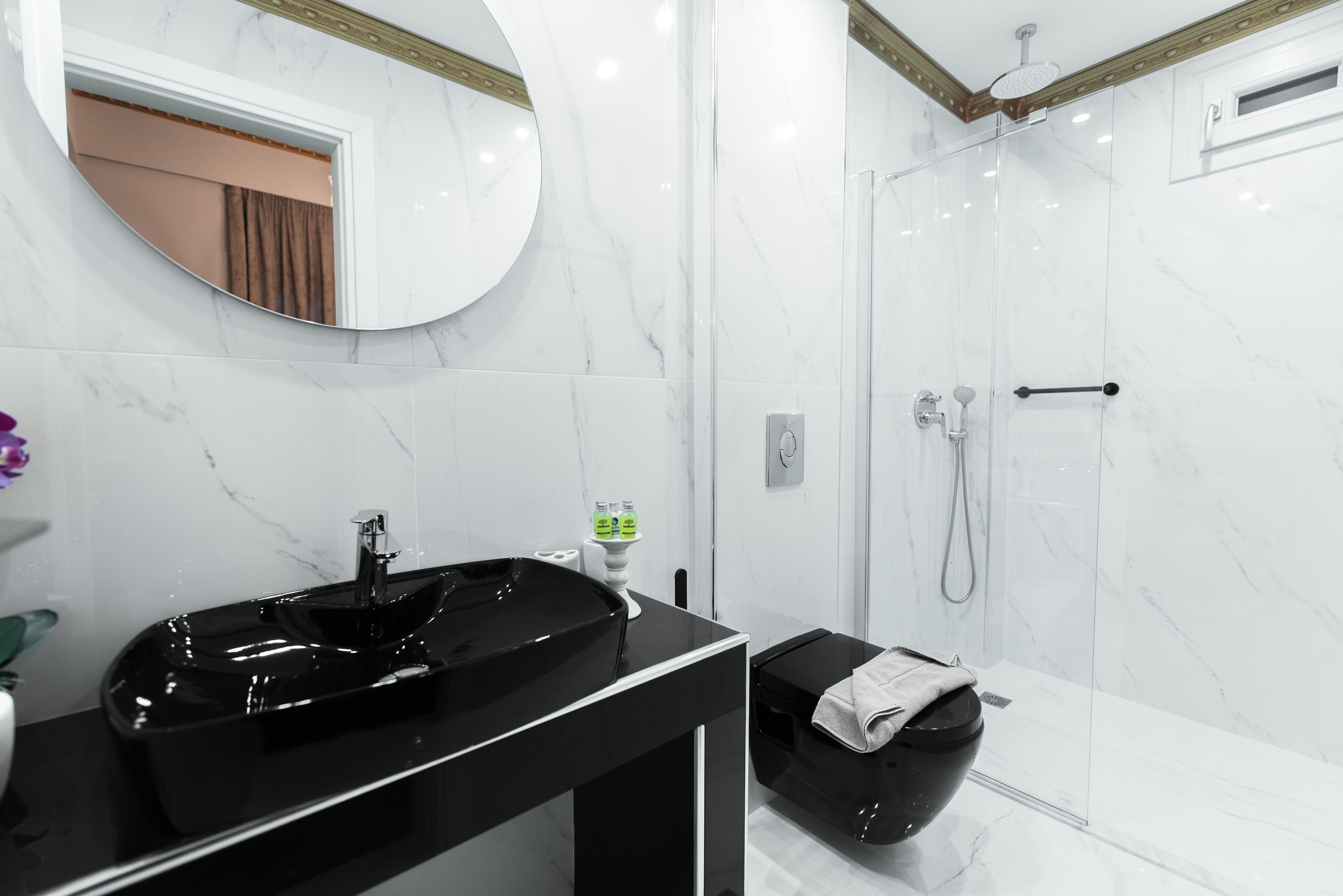 A modern bathroom with a black sink, a mirror, and a glass-enclosed shower.