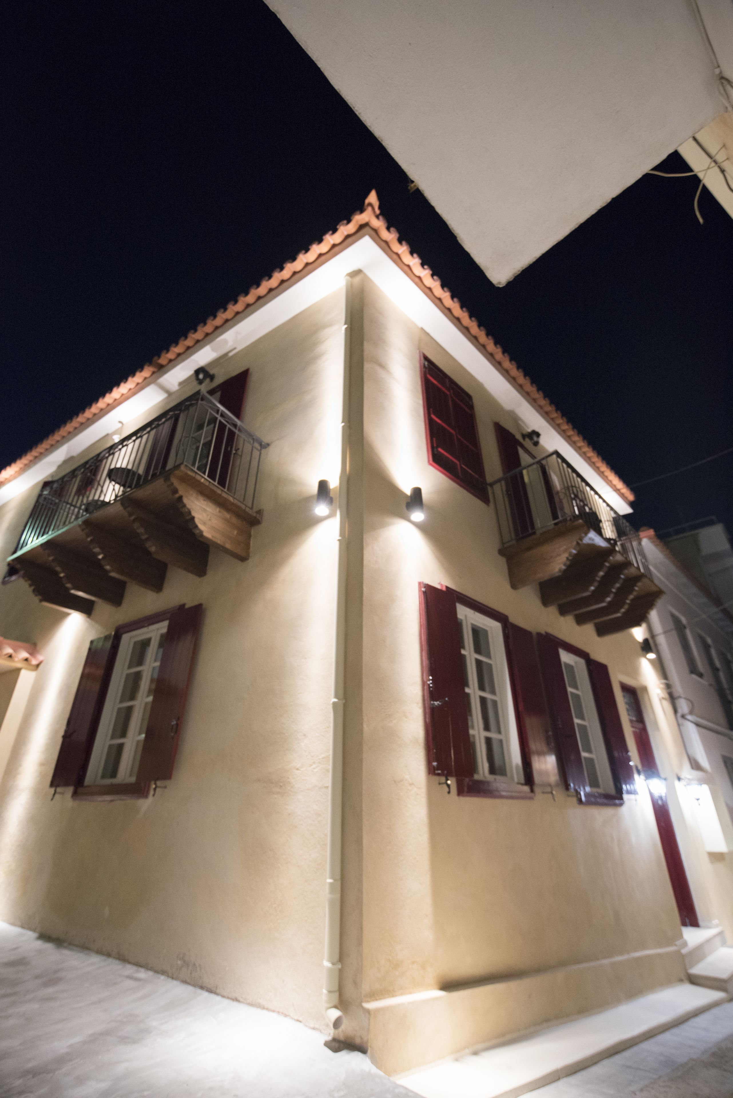 A building with a beige facade, red shutters, and a tiled roof.