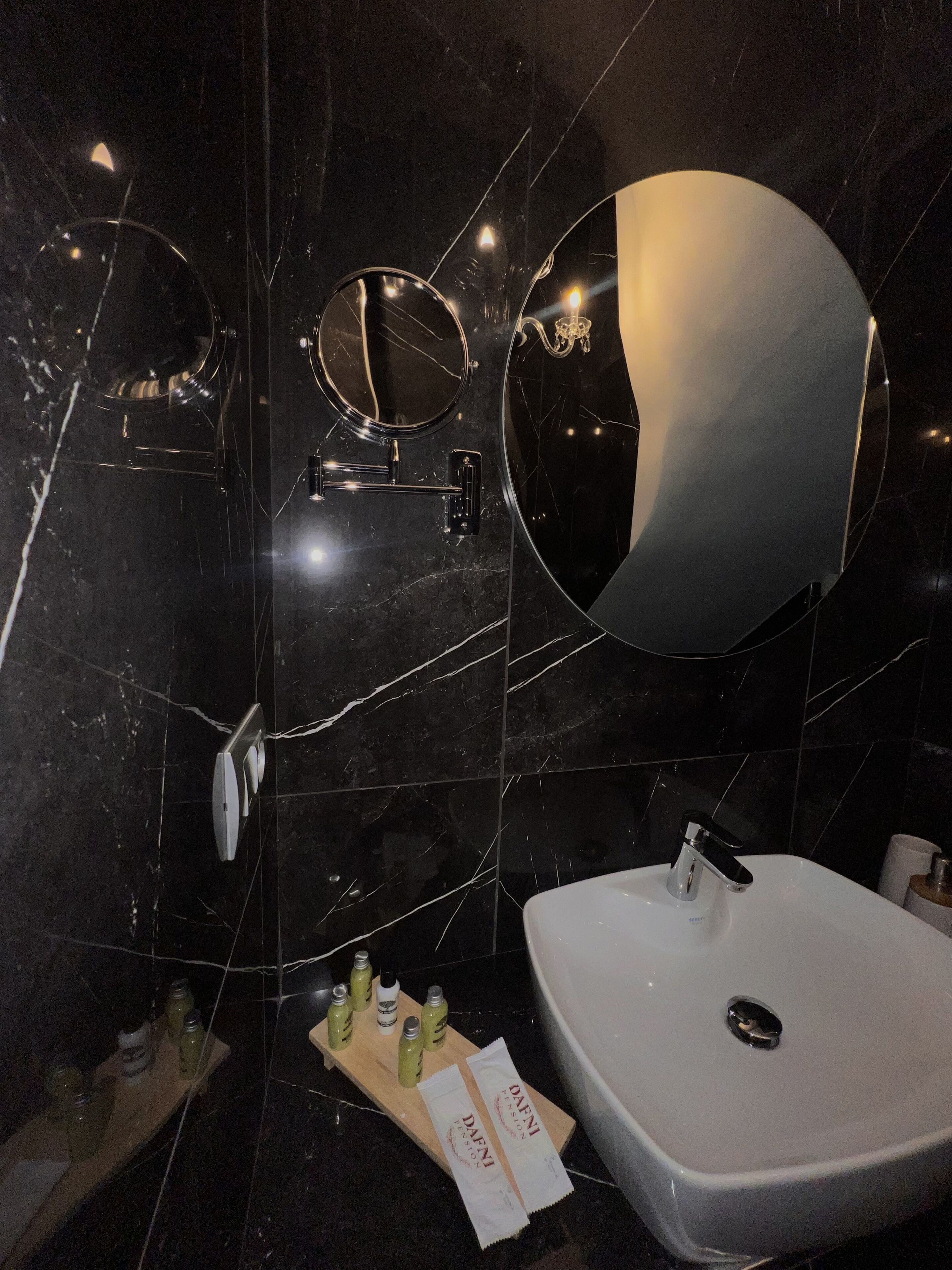 Une salle de bain avec un lavabo blanc, un grand miroir et une commode contenant des articles de toilette.
