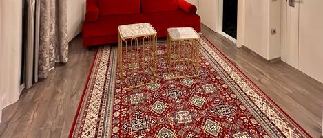 A room with a red sofa, patterned carpet, and a chandelier.
