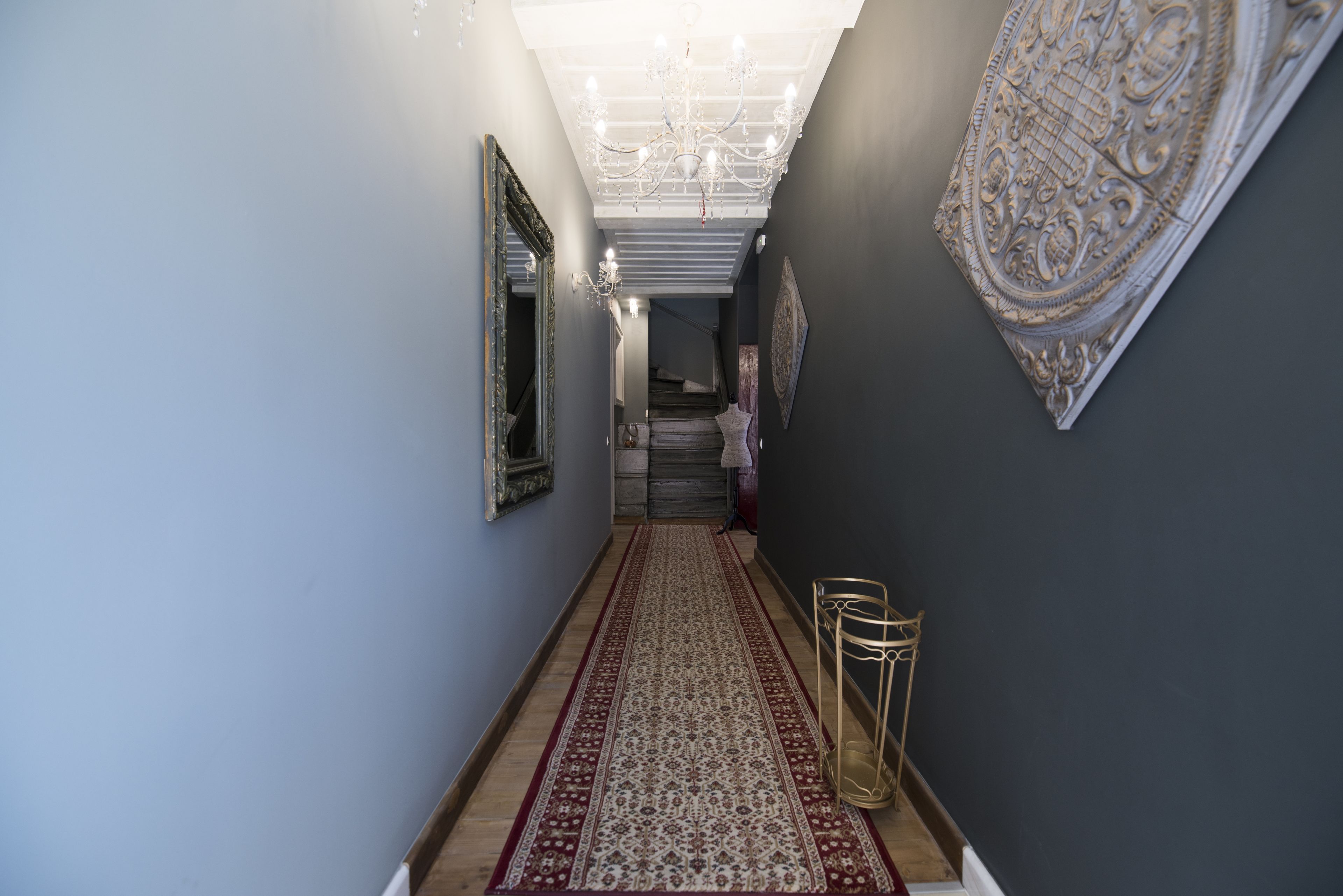 A hallway with a patterned carpet, a chandelier, and wall decorations.