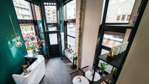A modern interior with a reception desk, two round tables, and shelves with decorative items. - Linden Hotel (Amsterdam)