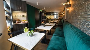 A modern restaurant with a green wall, marble tables, and a teal sofa. - Linden Hotel (Amsterdam)