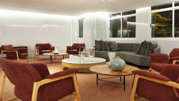 Una sala de estar moderna con un sofá gris, sillones rojos y una mesa de centro redonda.