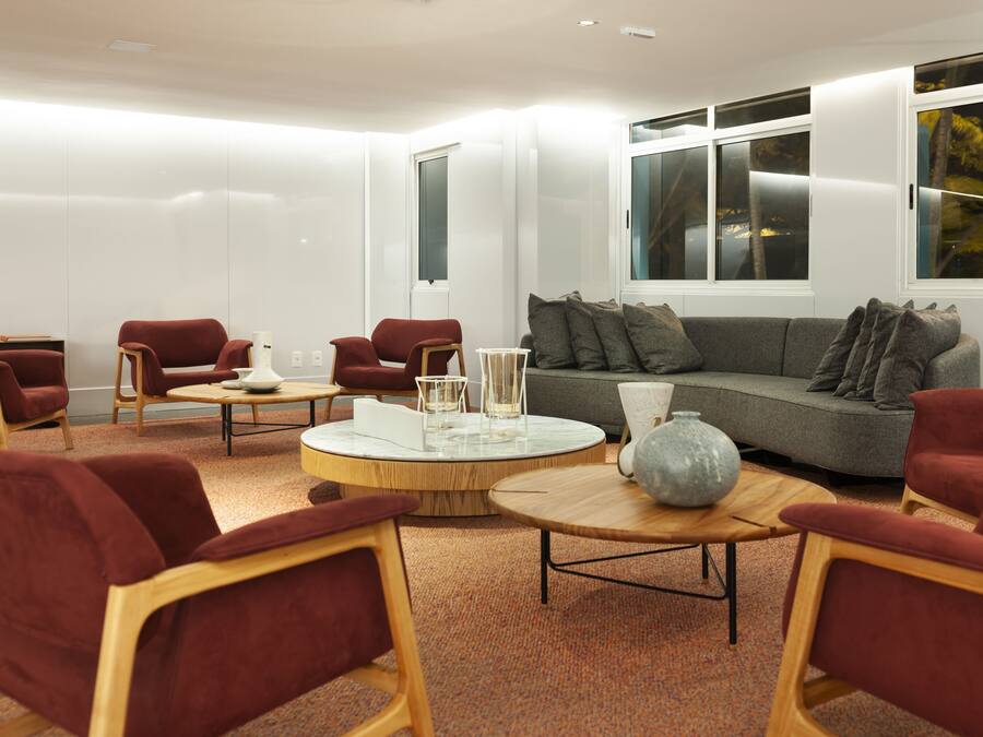 Una sala de estar moderna con un sofá gris, sillones rojos y una mesa de centro redonda.