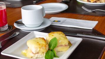 Una mesa de comedor dispuesta con platos de comida, una taza y cubiertos.