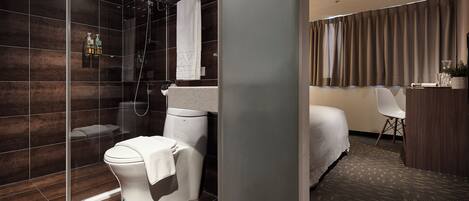 A modern bathroom with a glass-enclosed shower, a toilet, and a sink.