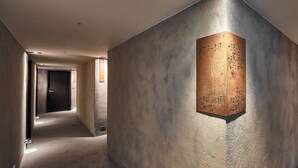 A hallway with a textured wall and a wooden plaque with numbers. - Via Hotel Loft (Taipei)