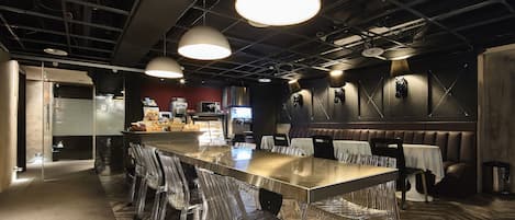 A modern conference room with a long table, clear chairs, and pendant lighting.