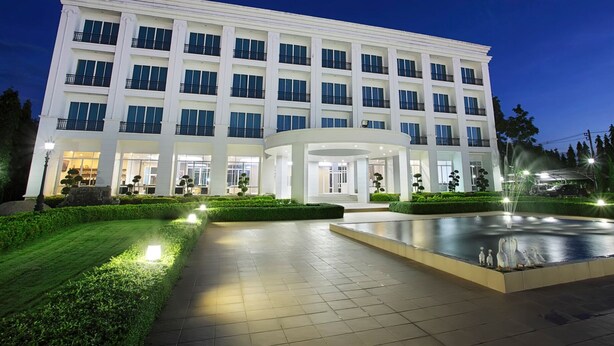 A large, multi-story hotel with a central courtyard featuring a fountain and a swimming pool. - La Vie En Rose Hotel (Chiang Rai)