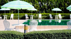 Outdoor seating with tables and chairs, a pool, and umbrellas. - La Vie En Rose Hotel (Chiang Rai)