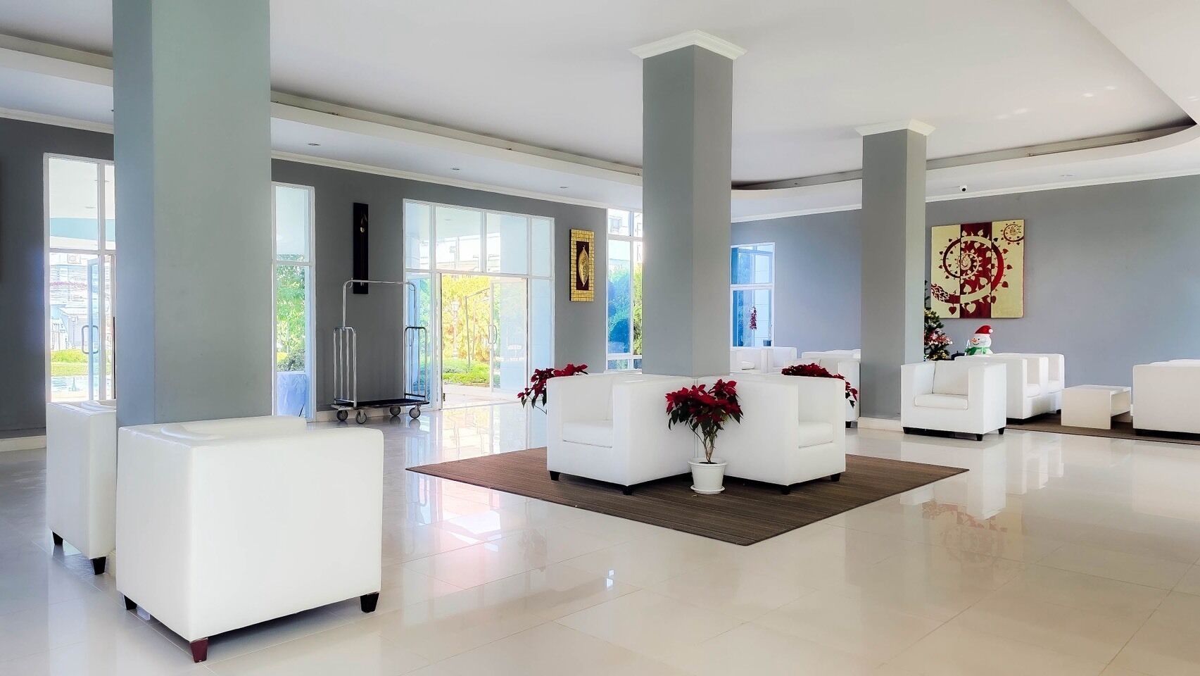 A spacious lobby with white sofas, a reception desk, and large windows allowing natural light.