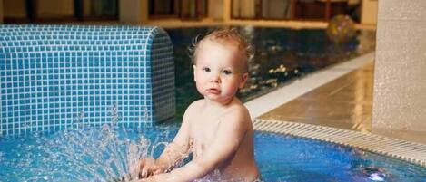 Un niño en una piscina rodeado de agua salpicando.